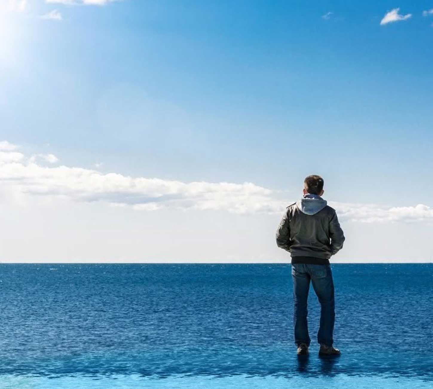 Homme contemplant l'horizon devant un océan calme